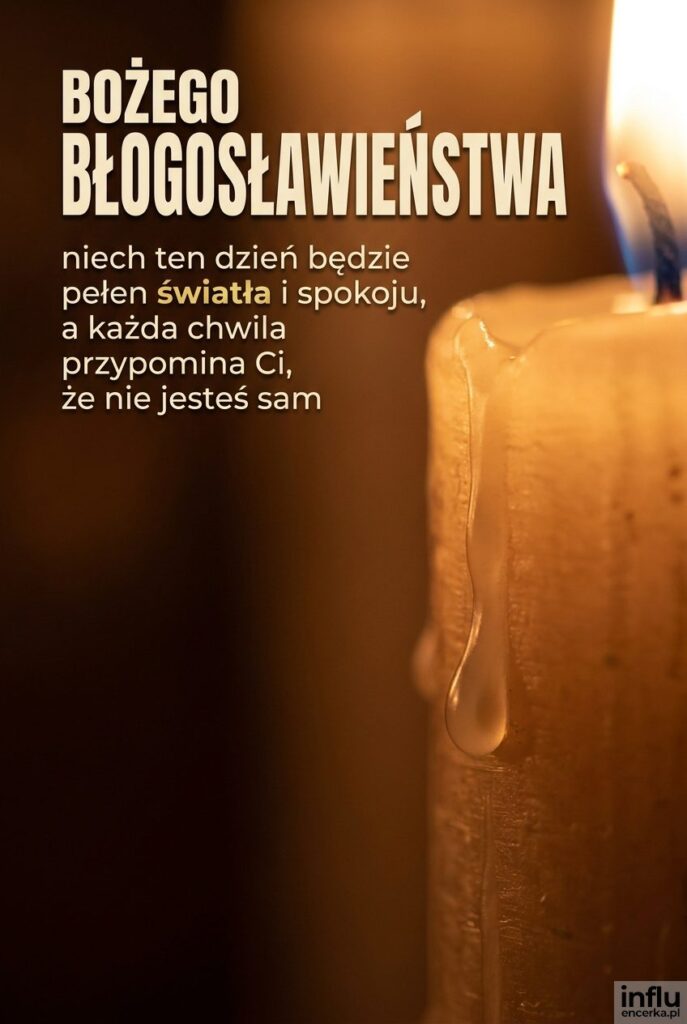 Zbliżenie płonącej świecy z napisem „Bożego błogosławieństwa" na rozmytym ciemnym tle.