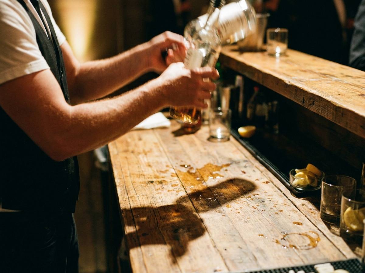 Barman prezentujący pokaz z butelkami przy przenośnym barze na weselu