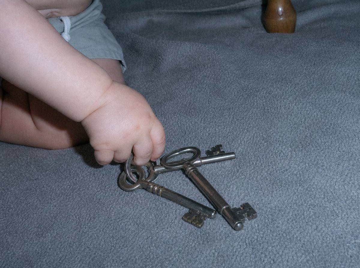 Pęk metalowych kluczy na kocu, dziecko chwyta jeden z nich