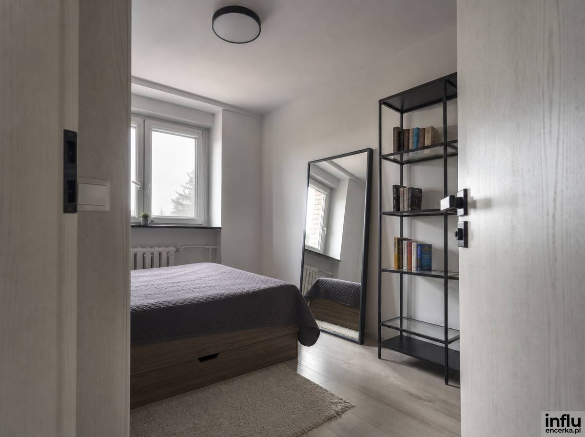 Kompaktowa sypialnia loft w bloku z jasnymi ścianami i dużym lustrem powiększającym wnętrze