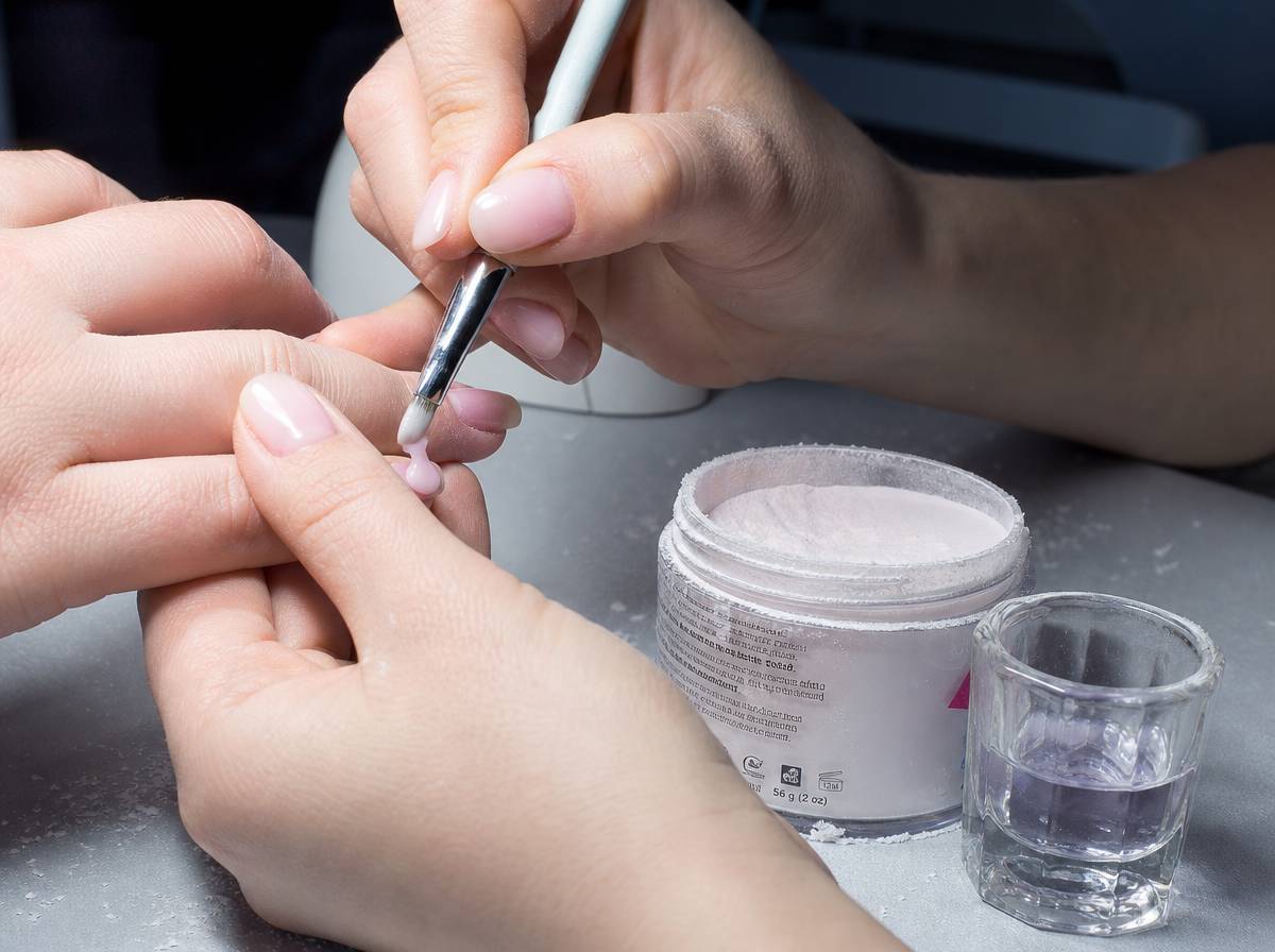 Nakładanie masy akrylowej pędzelkiem na płytkę paznokcia podczas stylizacji