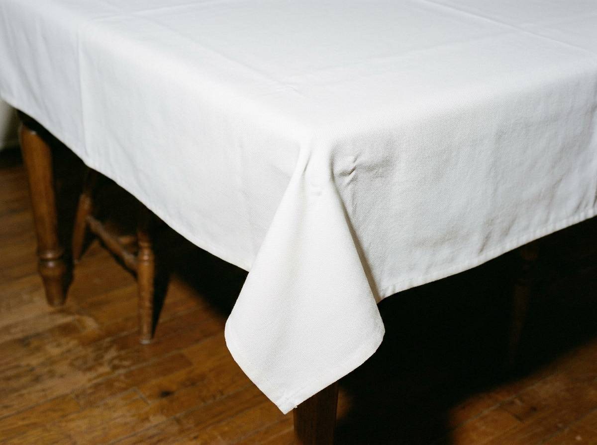 Biały matowy obrus plamoodporny zakrywający stół na chrzciny