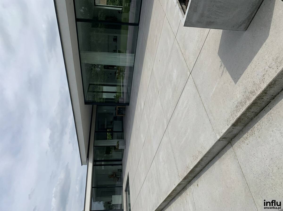 Taras z wielkoformatowych płyt betonowych w jasnym szarym kolorze przy nowoczesnym domu
